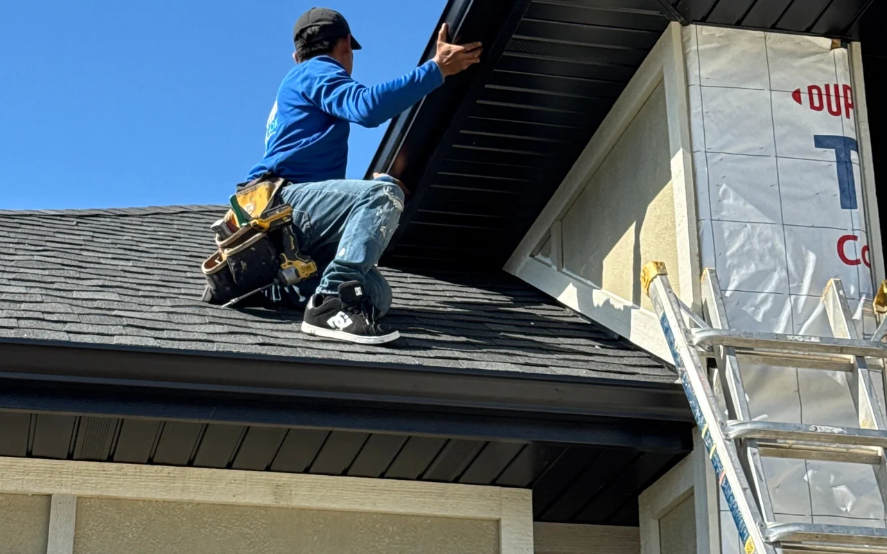 Seamless dark gutter and vented soffit detail along a modern home roofline under a bright blue sky