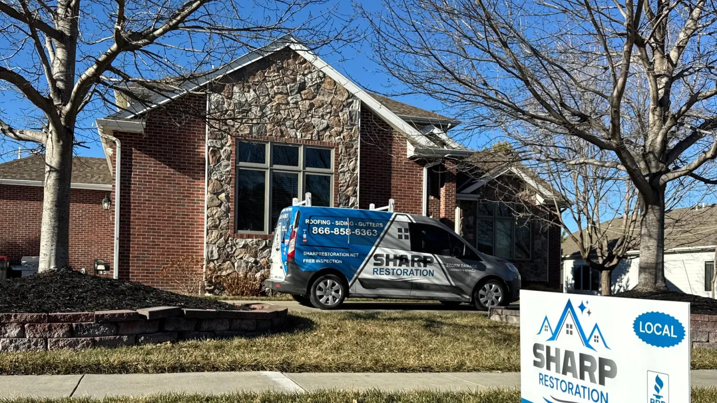 Sharp Restoration branded van and yard sign outside a Nebraska home during a roof replacement