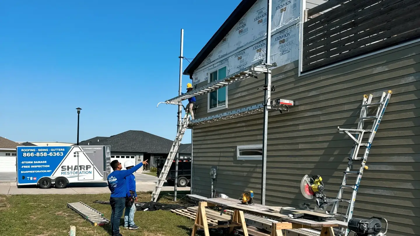 Sharp Restoration crew working from scaffolding on a full siding replacement in Nebraska