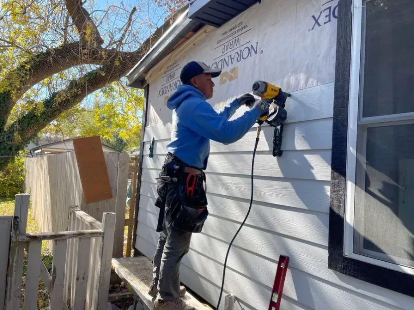 Sharp Restoration installer fastening new siding panels on a Nebraska home