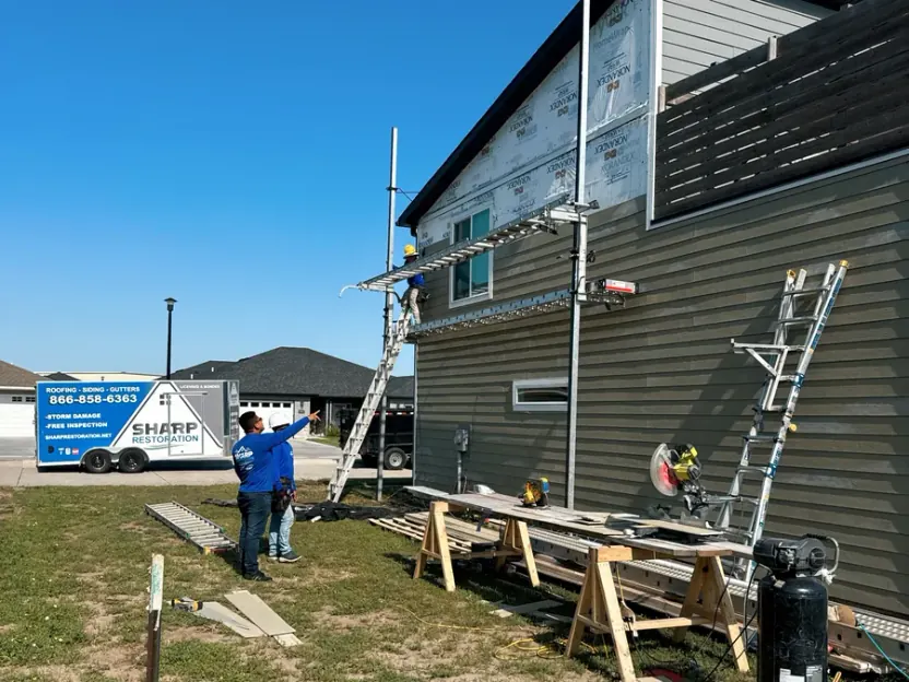 Sharp Restoration crew working from scaffolding on a full siding replacement